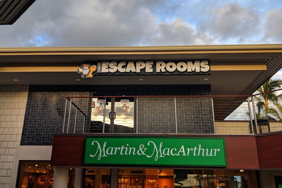 Looking up at a building, the top one with a sign that says "Escape Rooms" and one below that says "martin and MacArthur."