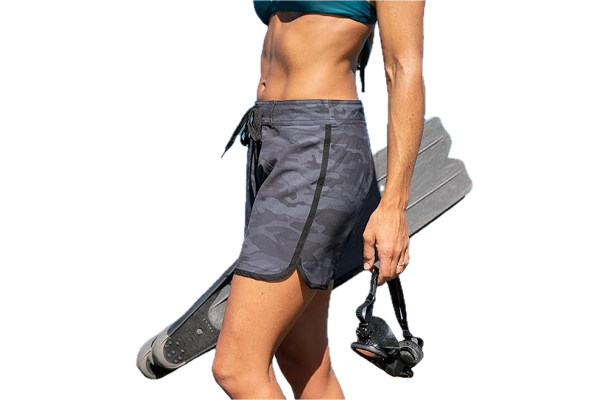 A woman carrying water skis, wearing a pair of camo board shorts.