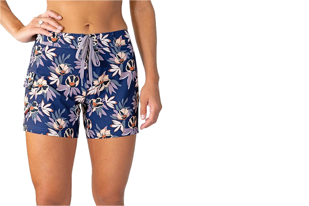 An image of a woman's lower body, wearing a pair of navy blue floral swim shorts.