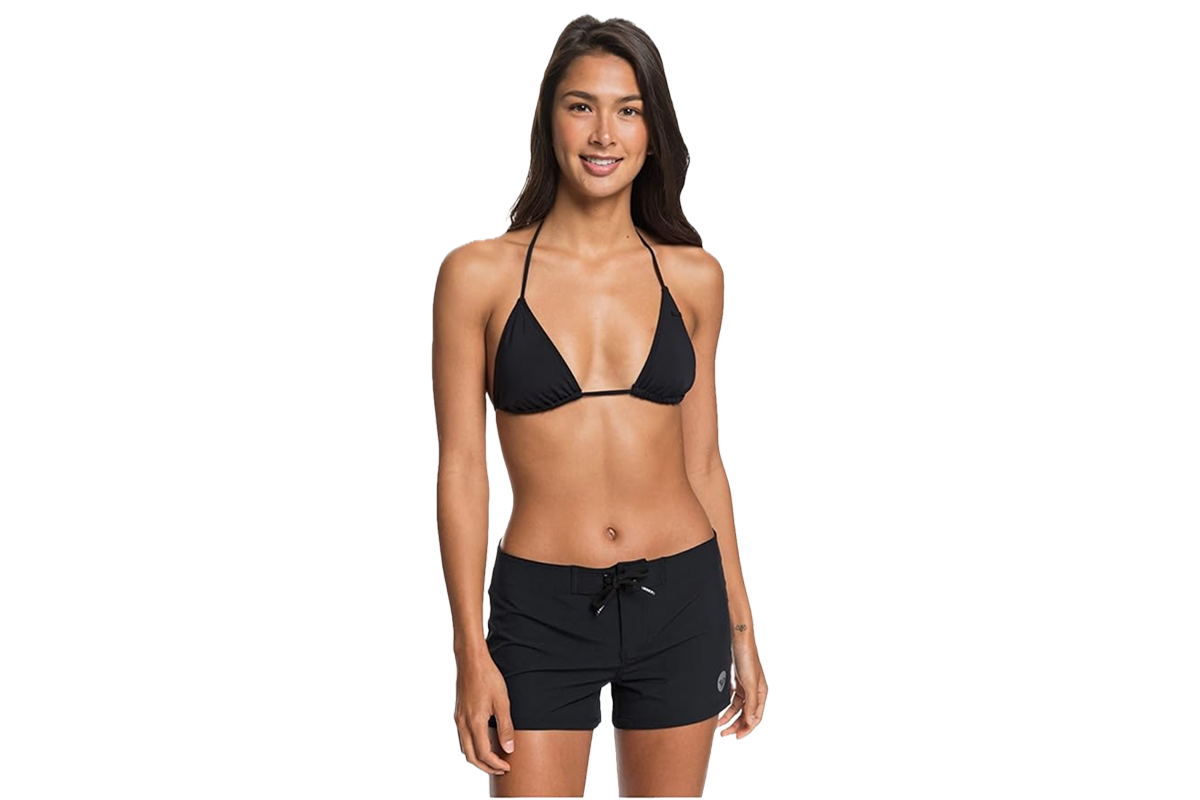 A woman wearing a black bikini top and black board shorts.