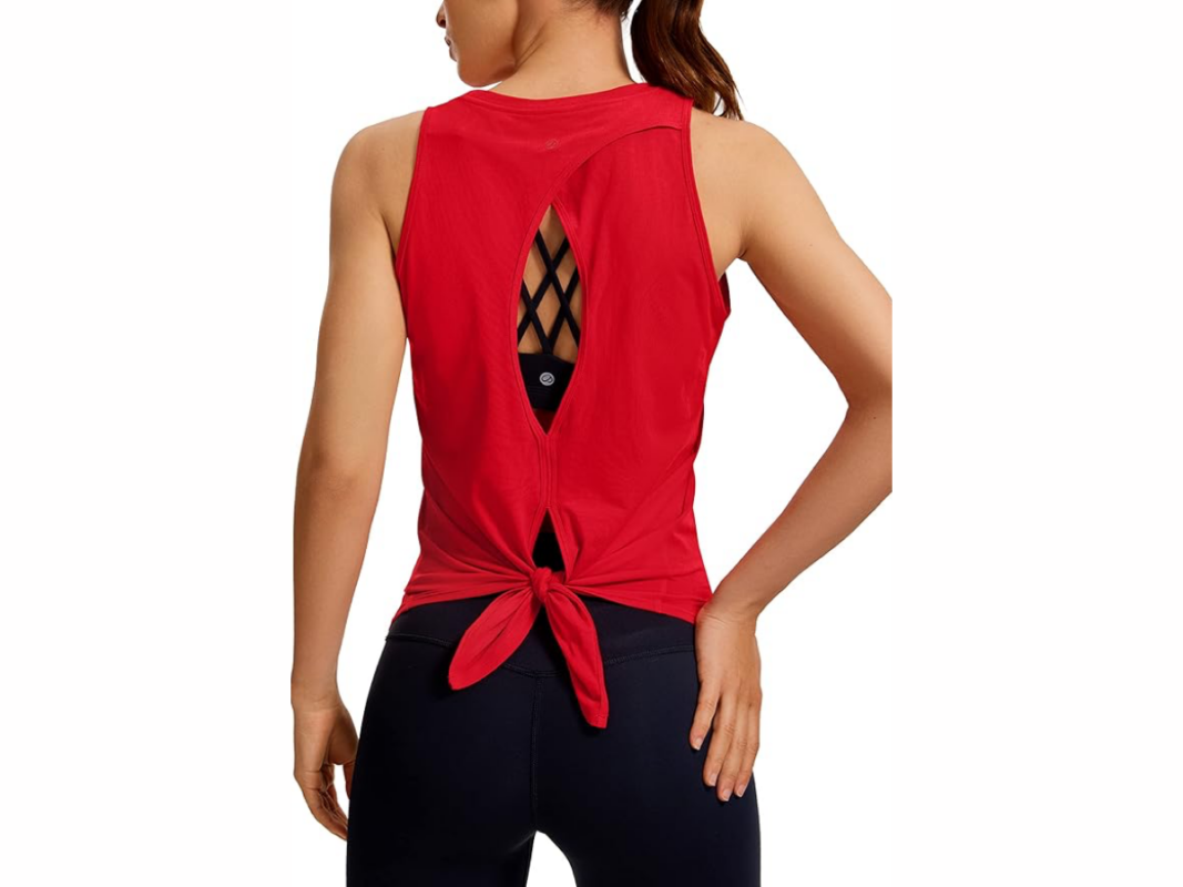 This image features the upper body of a woman, back towards us, wearing a red sleeveless workout top with an open back and tied at the waist.
