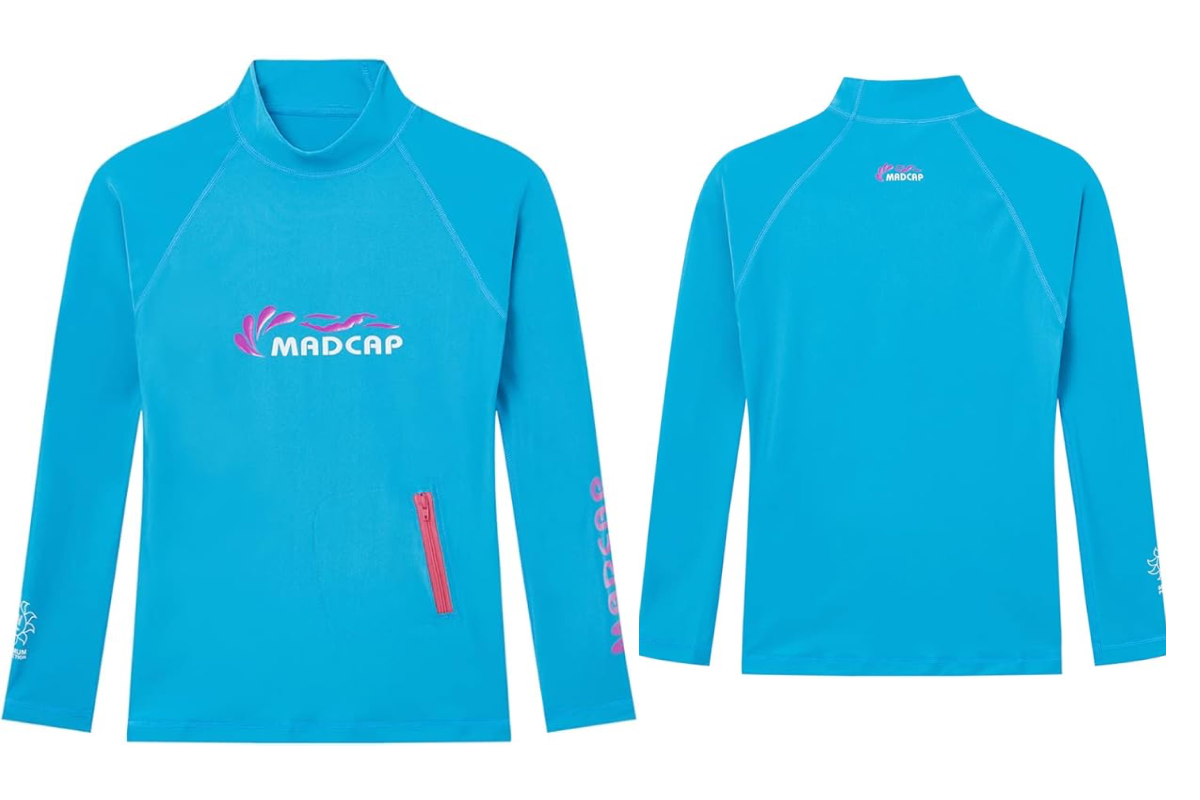 This image shows the front and back views of a bright blue long-sleeve rash guard with a high collar. Perfect as one of the UV tops for teens, it features "MADCAP" in white on the front and a small pink zipper pocket. The back displays the logo in the upper center, and the left sleeve has pink text.