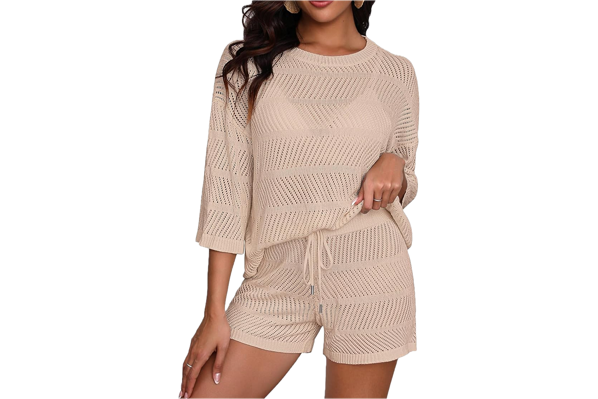 A woman wearing a two piece, shorts and long sleeve crochet set in the color nude.