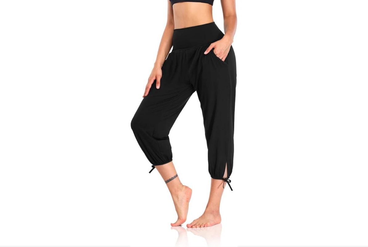 This image features a woman's lower body wearing cropped, loose, black yoga pants with ties mid-calf.