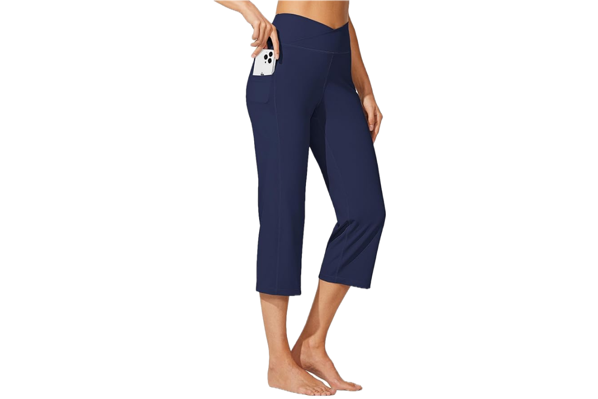 This image features the lower bottom of a woman, facing to the right, wearing a cropped, flare style pair of yoga pants in a blue.