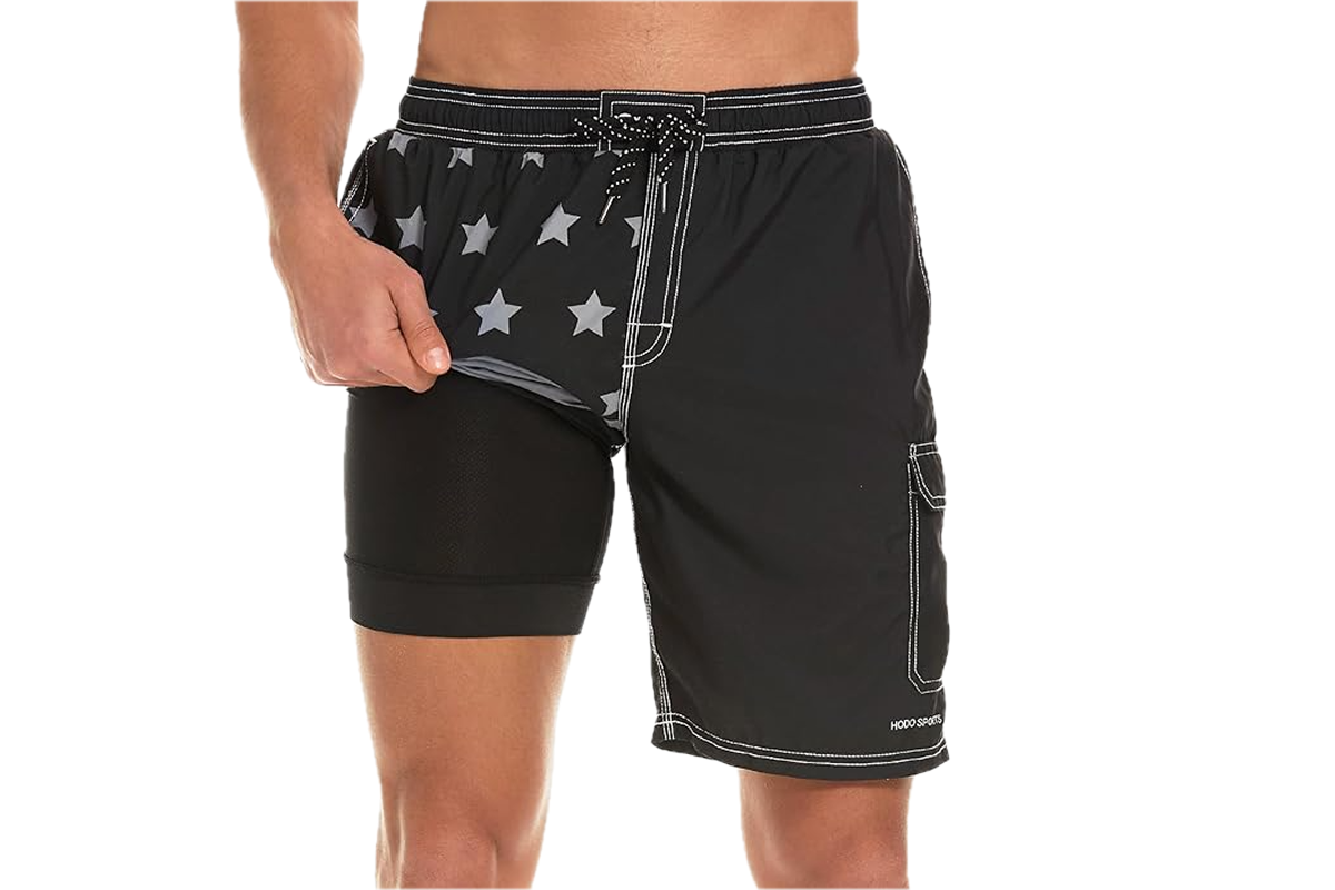 The lower torso of a man dressed in black swim trunks lined with a star print.