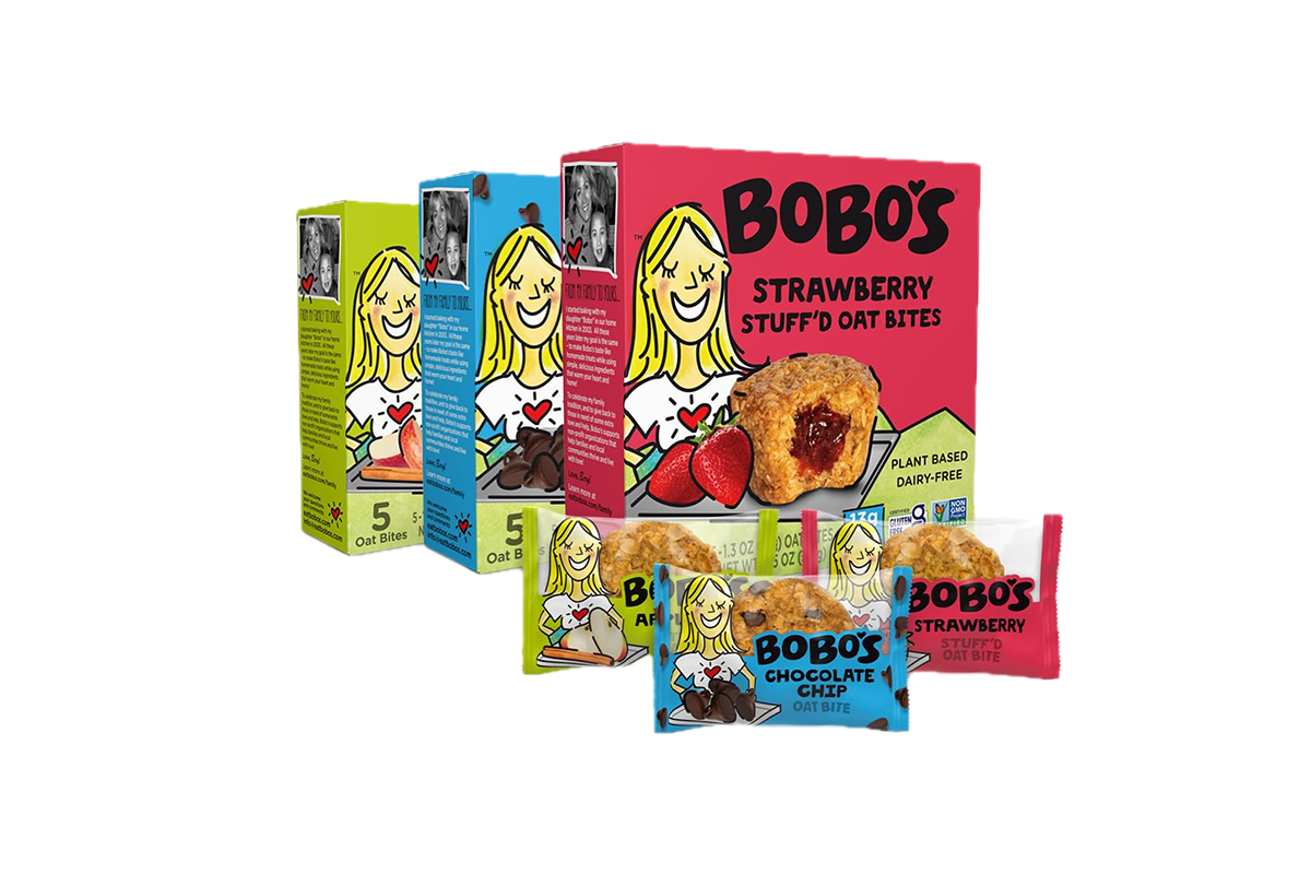 Boxes of Bobo's oat bites in different flavors: chocolate chip and strawberry. Each box features a cartoon blonde woman in a white shirt with a red heart. Several individually wrapped oat bites are placed in front of the boxes, making them perfect road trip snacks.
