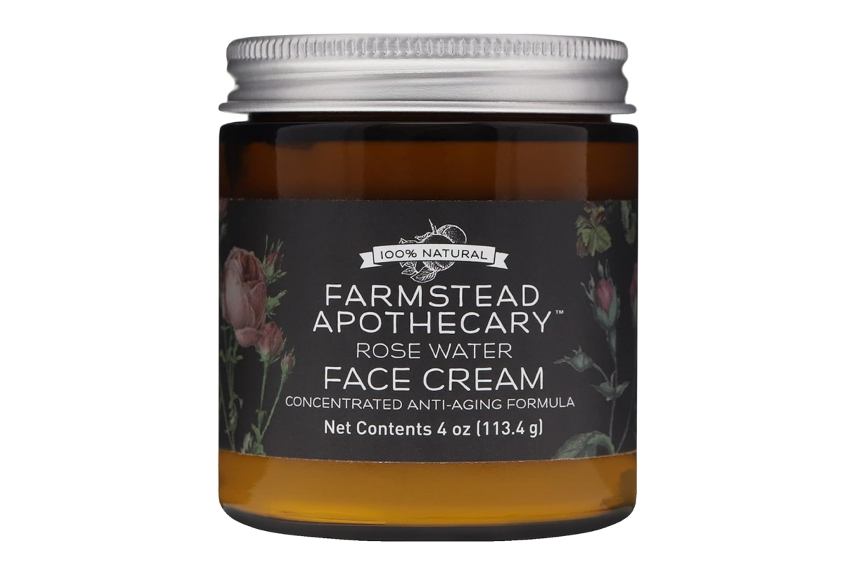 A 4 oz (113.4 g) jar of Farmstead Apothecary Rose Water Face Cream is shown. The jar has a metallic lid and an amber-colored body with a black label displaying the brand name, product details, and a floral design. This eco-friendly beauty product is labeled as a concentrated anti-aging formula.
