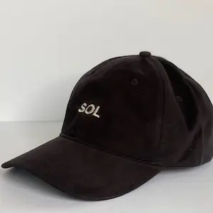 A black baseball cap with "SOL" embroidered in white on the front. The cap has a curved bill and is placed against a plain, light-colored background, embodying the perfect blend of Sol Sister Sport elegance and functionality.