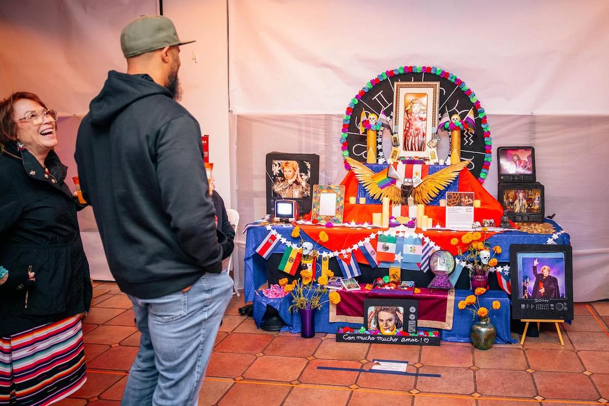 Two people look at an elaborate altar set up for Día de los Muertos event Avenida de Altares in San Jose, California