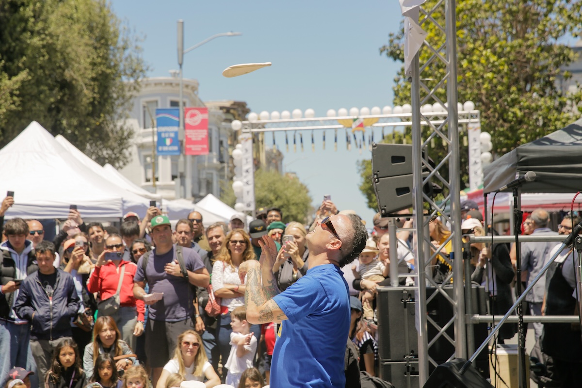 Tony of Tony's Pizza tosses a pizza dough in front of a crowd at San Francisco's Festa Italiana