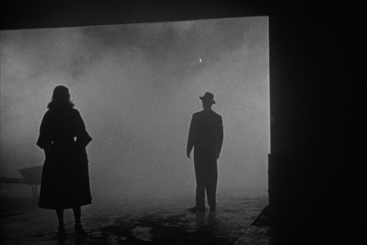 Film still from The Big Combo (1955) of silhouetted man and woman standing in foggy space