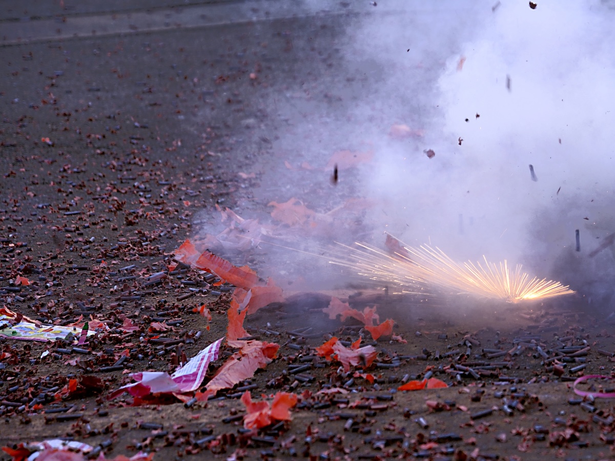 Firecracker detonating with sparks and smoke in street