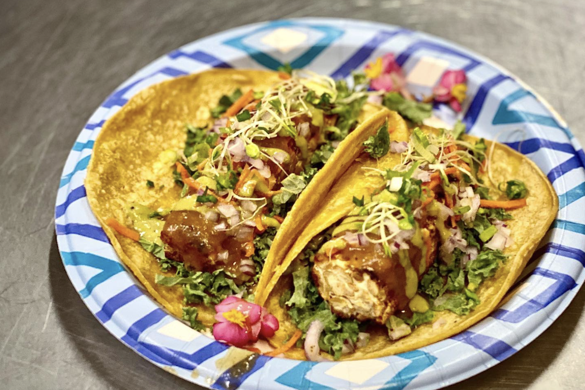 A paper plate with two loaded tacos.