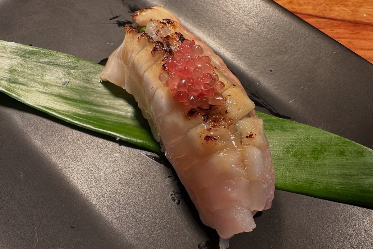 A cut of fish on a leaf and topped with roe.