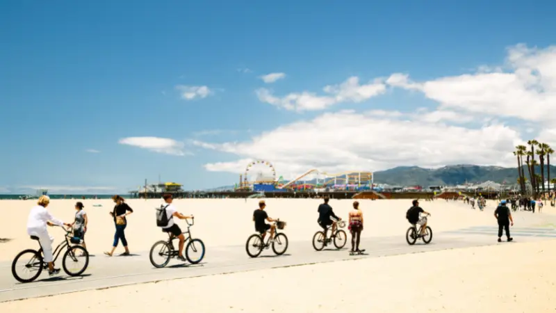 A group of people riding bicycles on a beach, as featured in The Ultimate Los Angeles Guide.