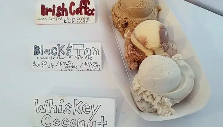 A tray holds three scoops of different flavored ice cream—possibly some of the best desserts Honolulu has to offer. Above it, handwritten signs list the flavors: "Irish Coffee: Kona Coffee, Irish Crème & Whiskey," "Black & Tan: Chocolate Stout + Pale Ale," and "Whiskey Coconut." Prices are shown on the Black & Tan sign.