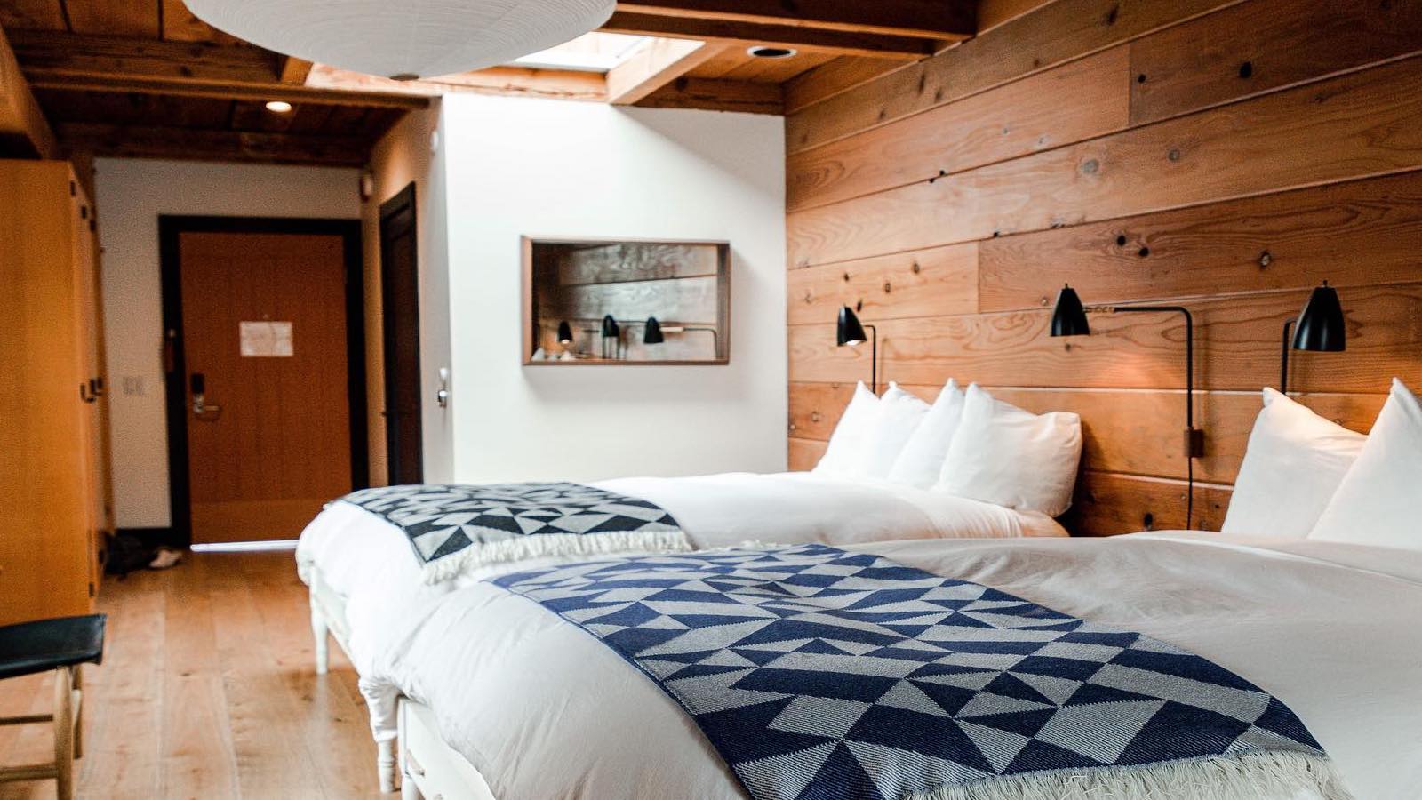 Hotel room with a bed, wood paneling on wall, and door.