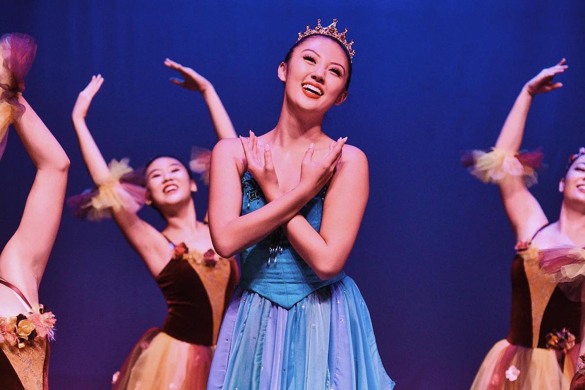 Dancers on stage perform for the Nutcracker Sweets show, with the main dancer wearing blue and the others wearing brown.