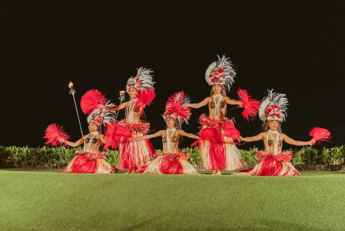 Luau for Te Au Moana, with performers wearing beads, headdresses, skirts and holding feather fans.