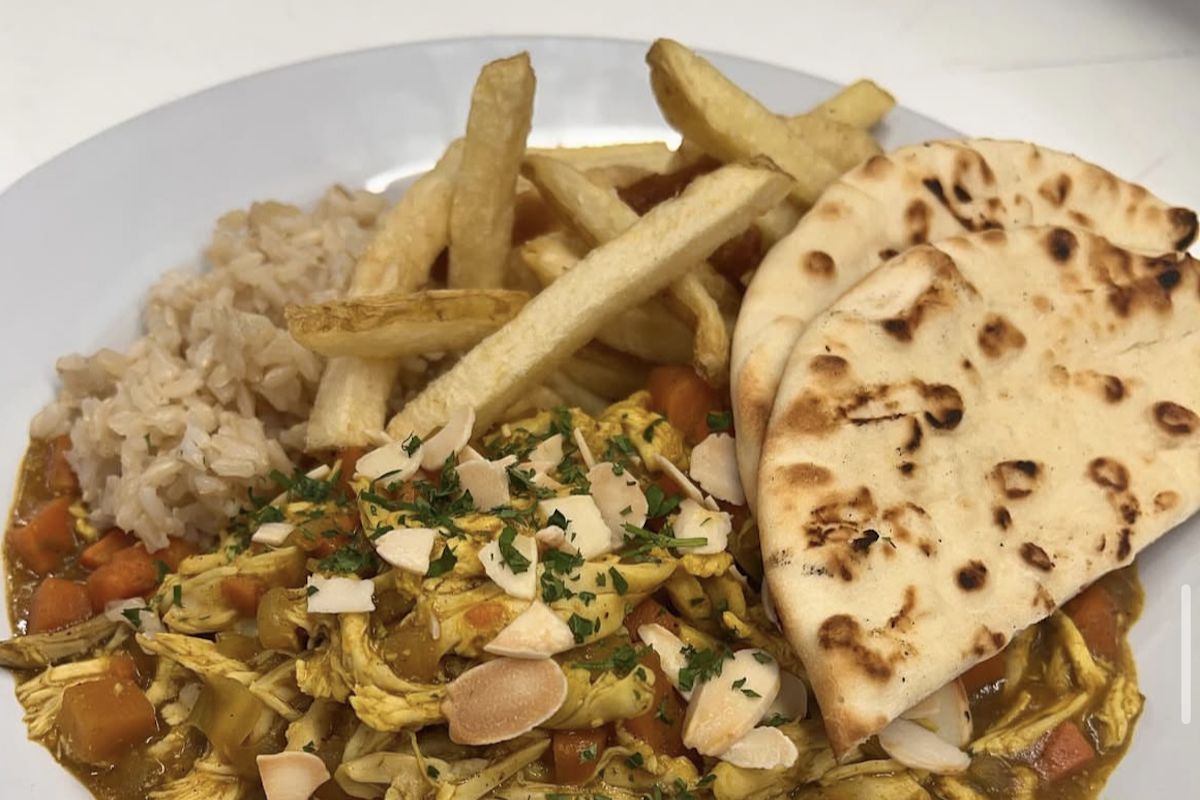 A plate with naan, chicken curry and handcut fries.