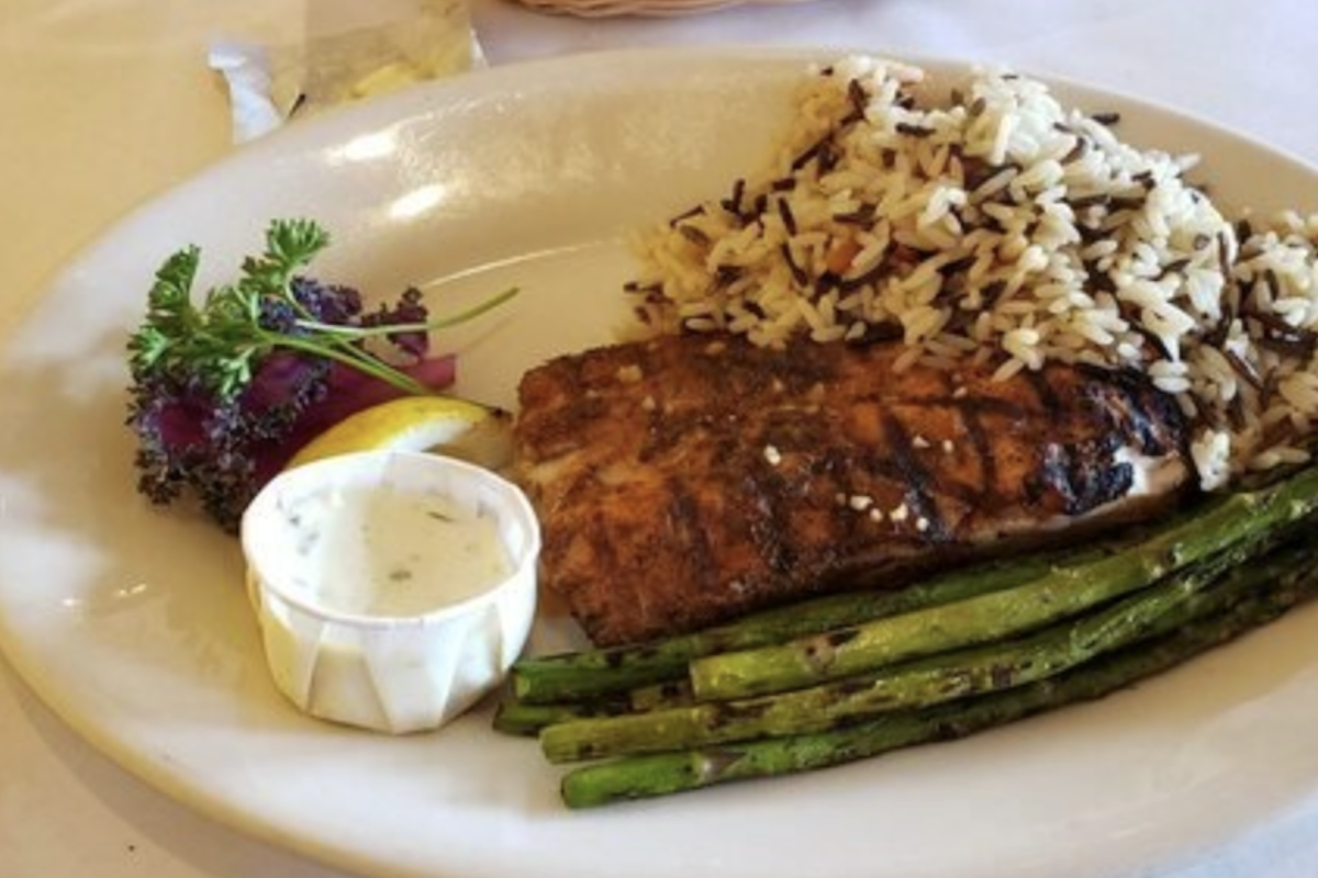 A filet with some roasted asparagus, rice medley, garnish and a little cup of sauce.