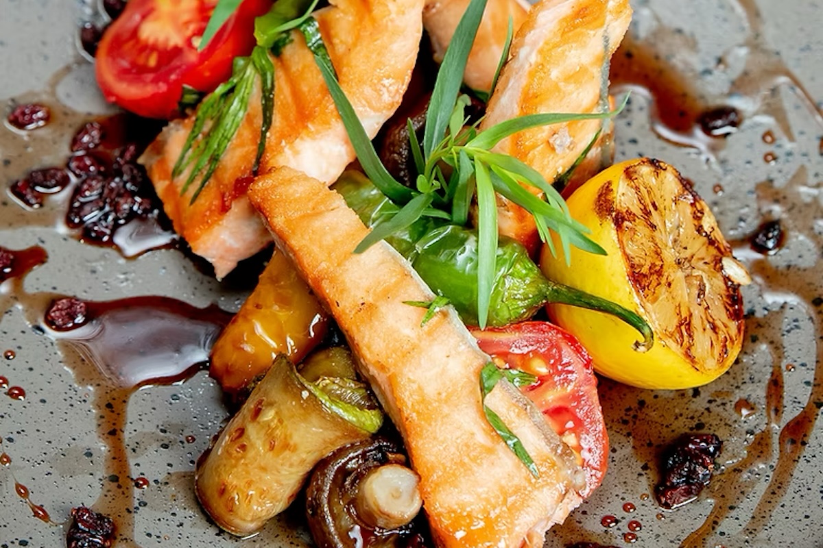 A plate of grilled seafood and veggies on a plate garnished with a brown sauce.