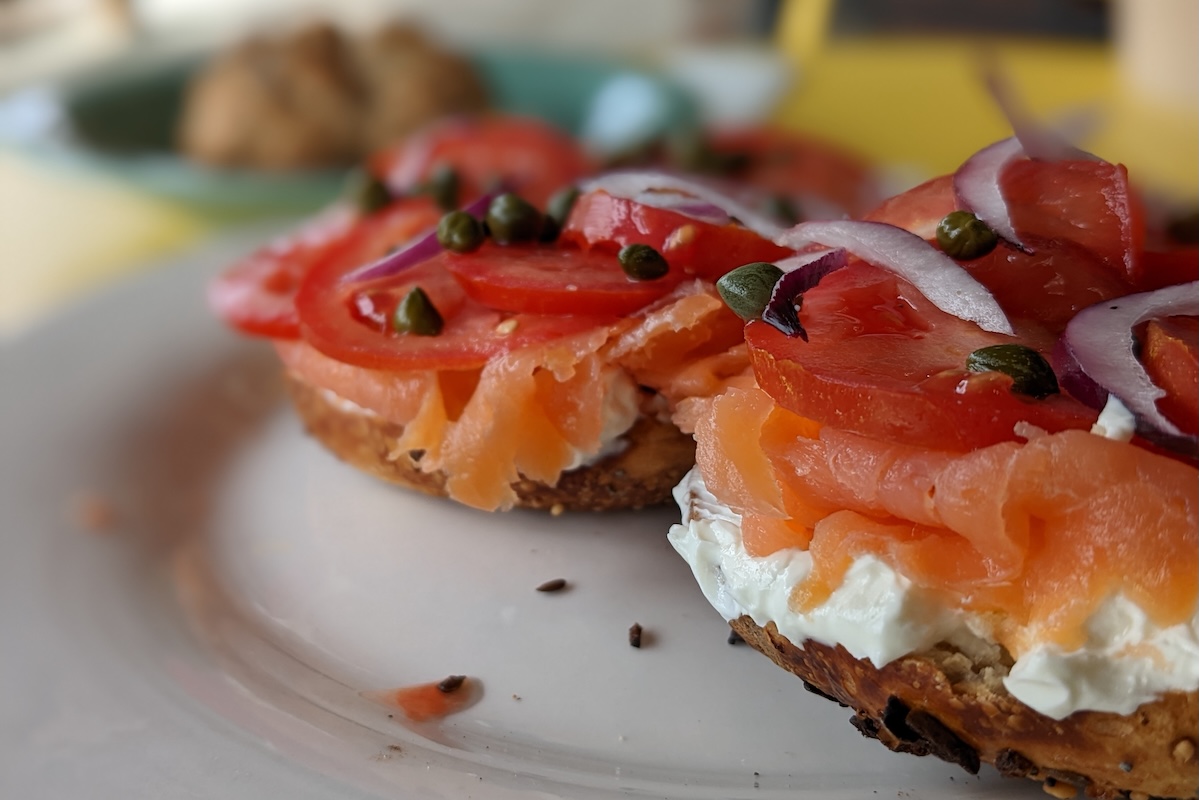 Two bagel halves with cream cheese, lox, capers and onions sit on a plate.