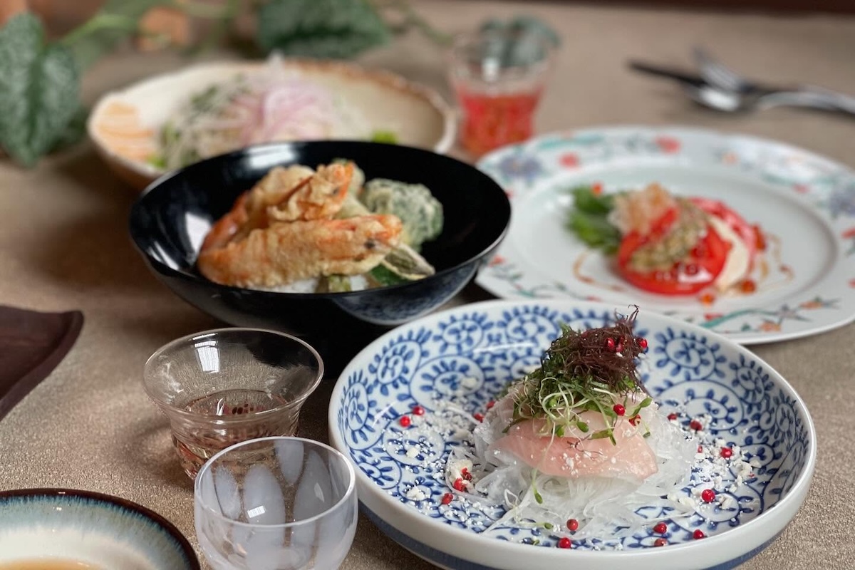 Various plates with elevated sushi and glasses of beverages.