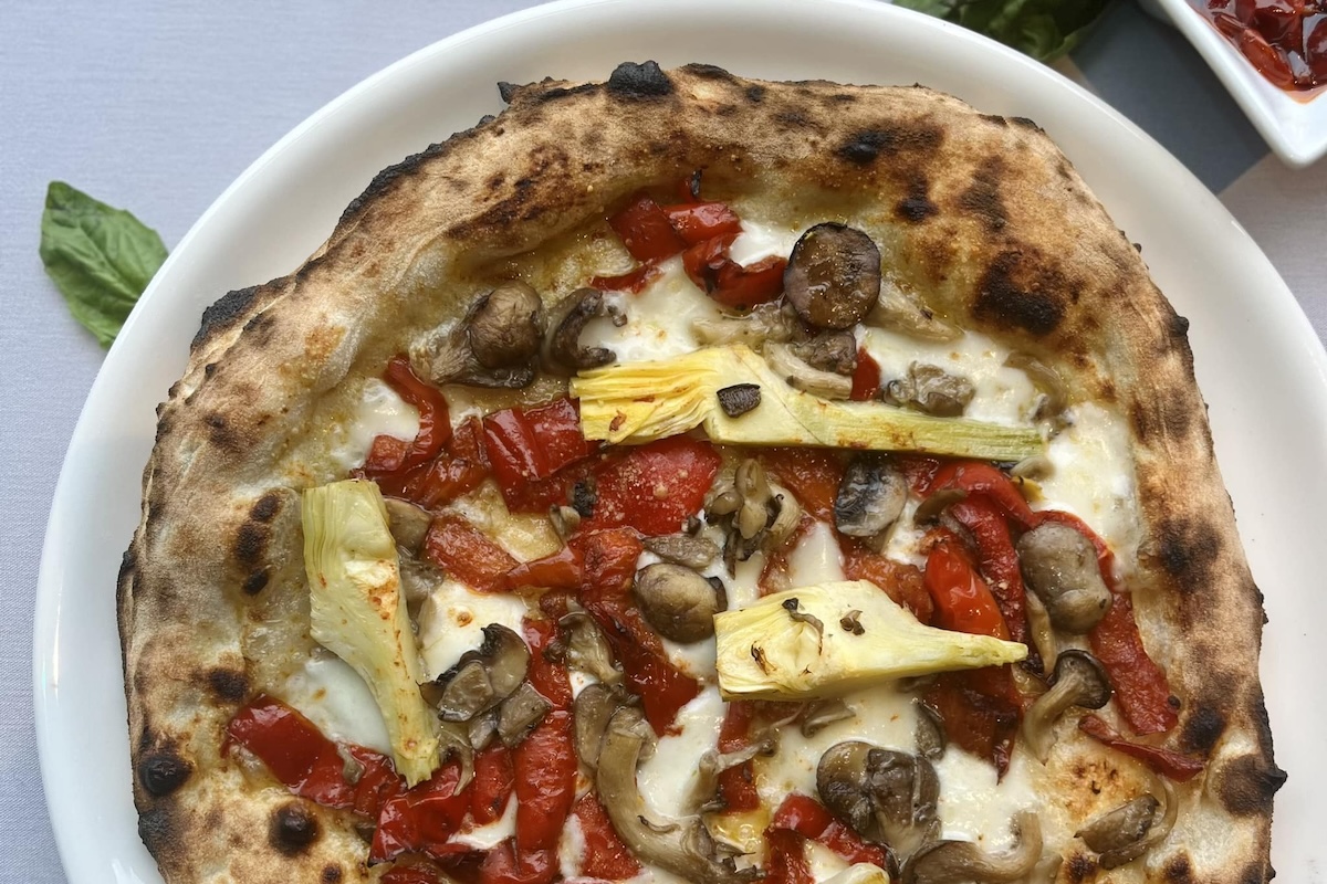 A pizza with artichokes, mushrooms, roasted red peppers and cheese.