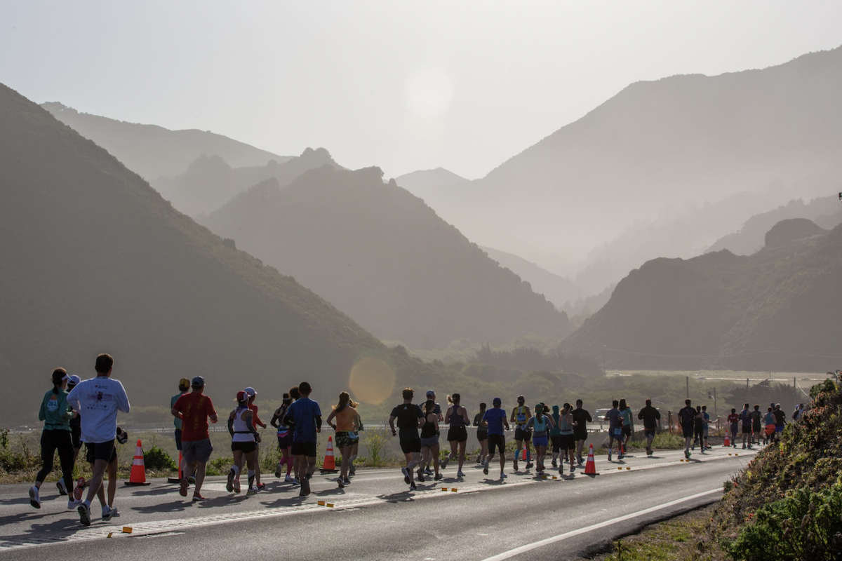 People running in a marathon on a road with a view of some rolling hills.