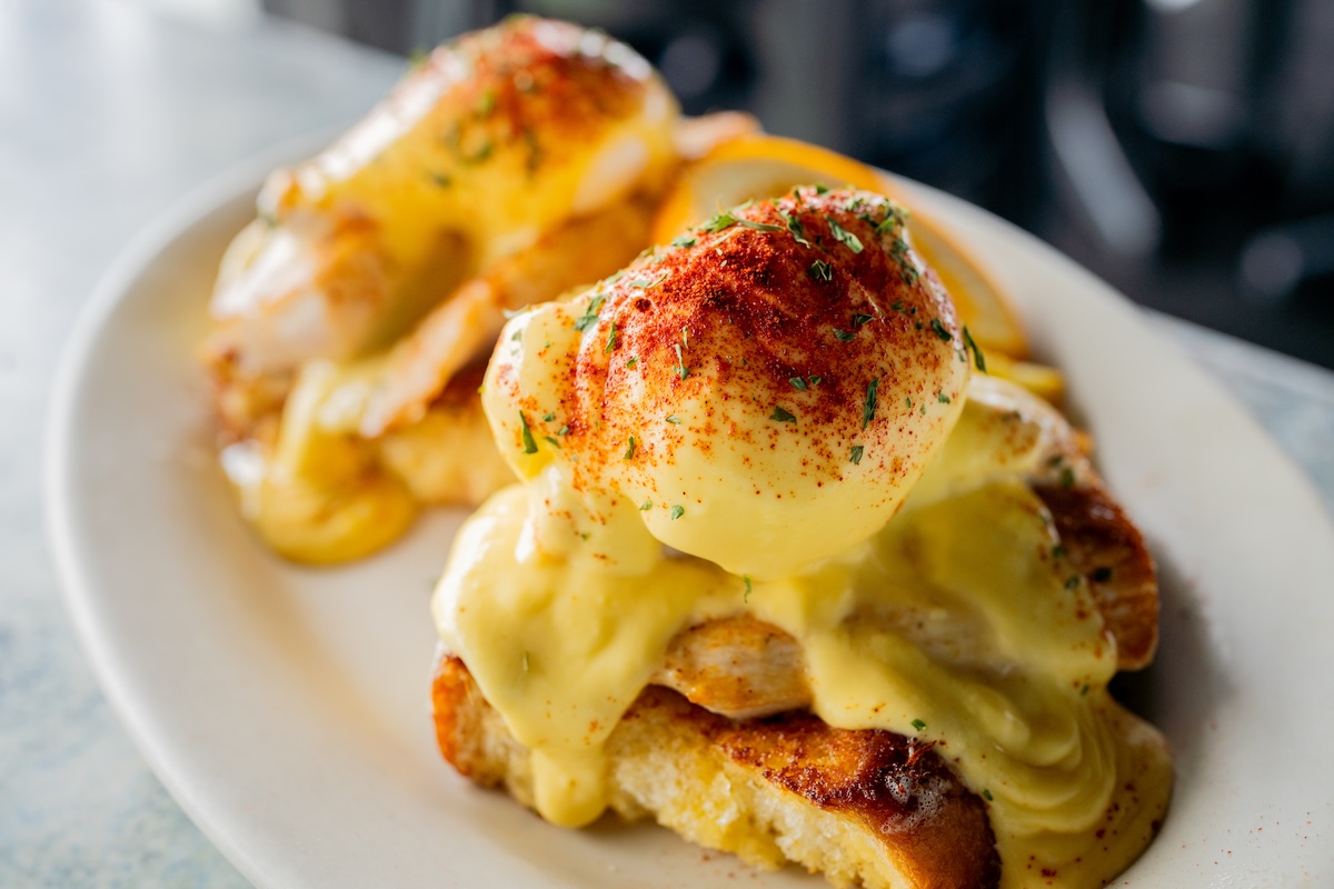 Eggs Benedict garnished with paprika and chopped herbs.
