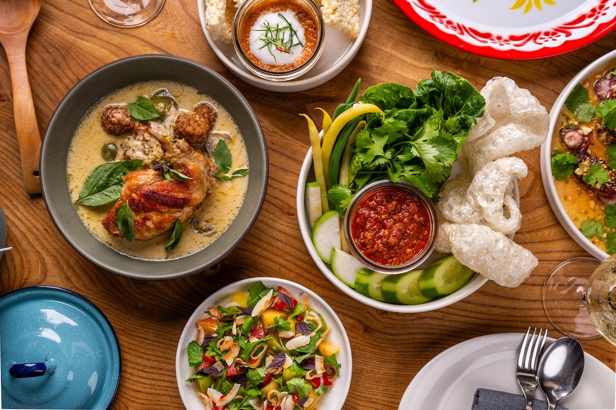 Bowls of food including soup with meat, salad, sliced veggies and more.