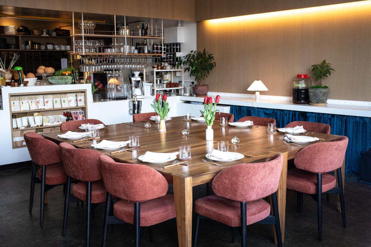 A restaurant with a wooden table and pink chairs.