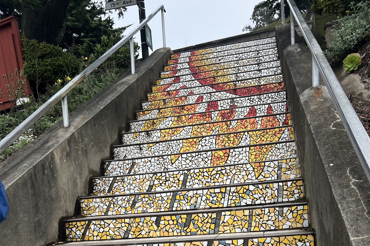 A view up at a staircase made with tiles that form the image of a sun.